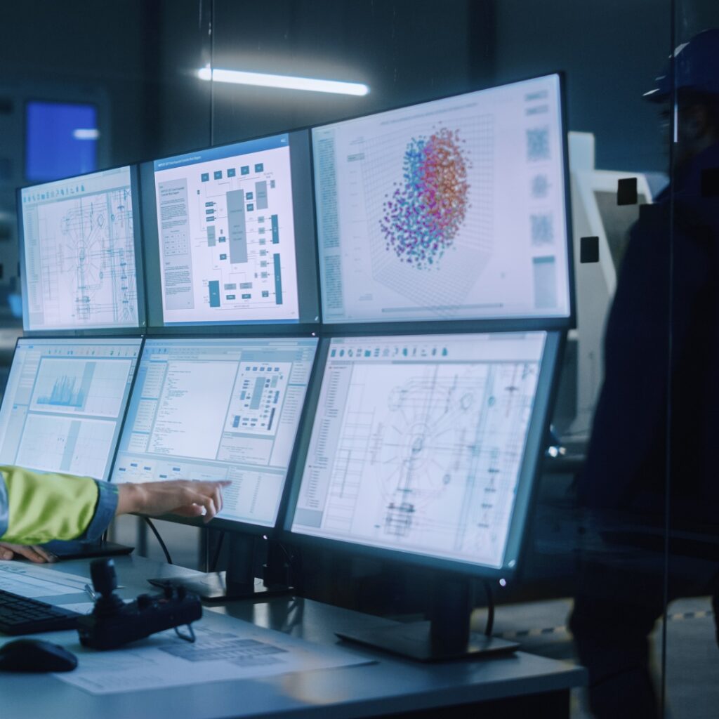 Ingenieurin zeigt auf Bildschirme einer Schaltzentrale